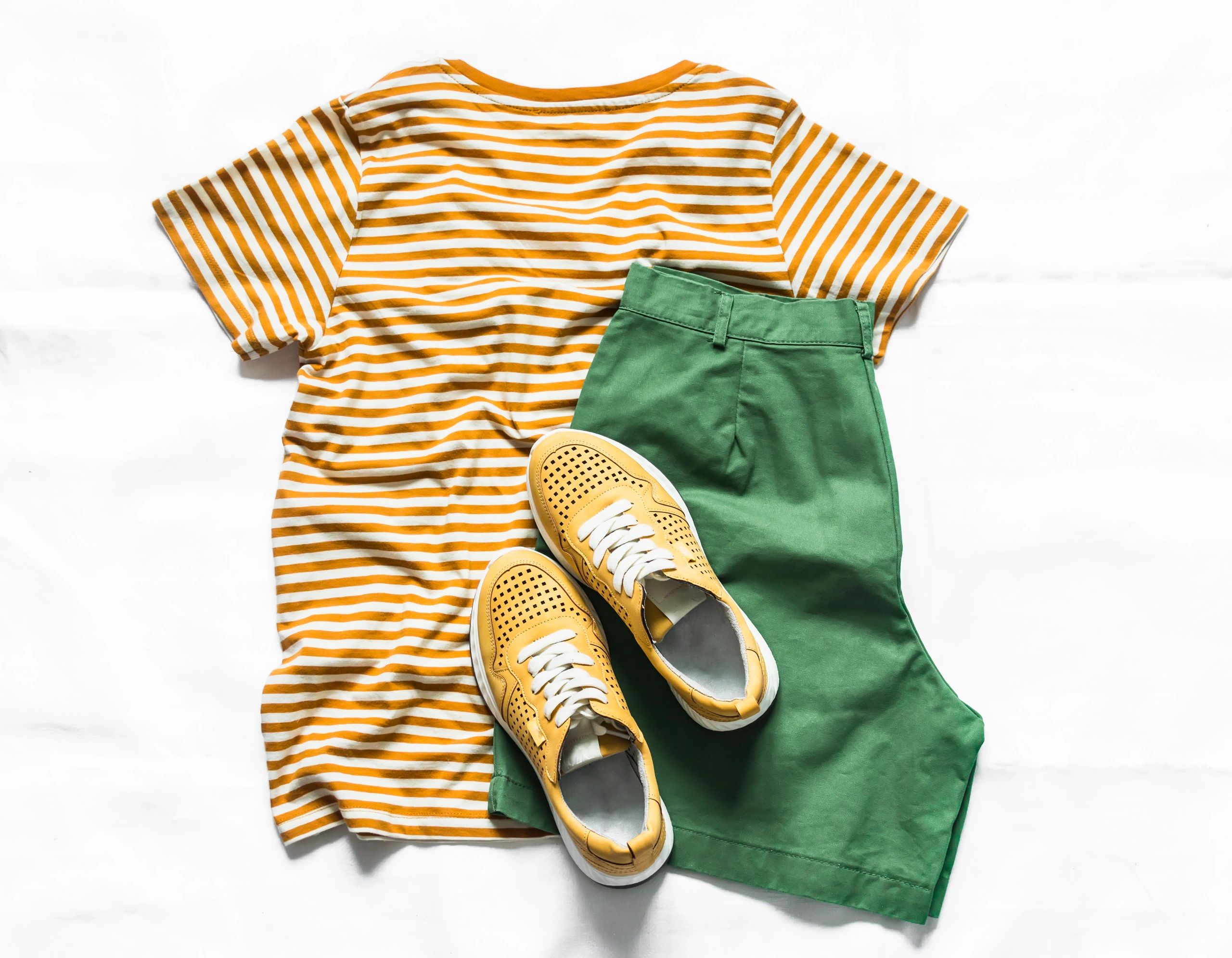 Flat lay of casual outfit with yellow t-shirt and sneakers.