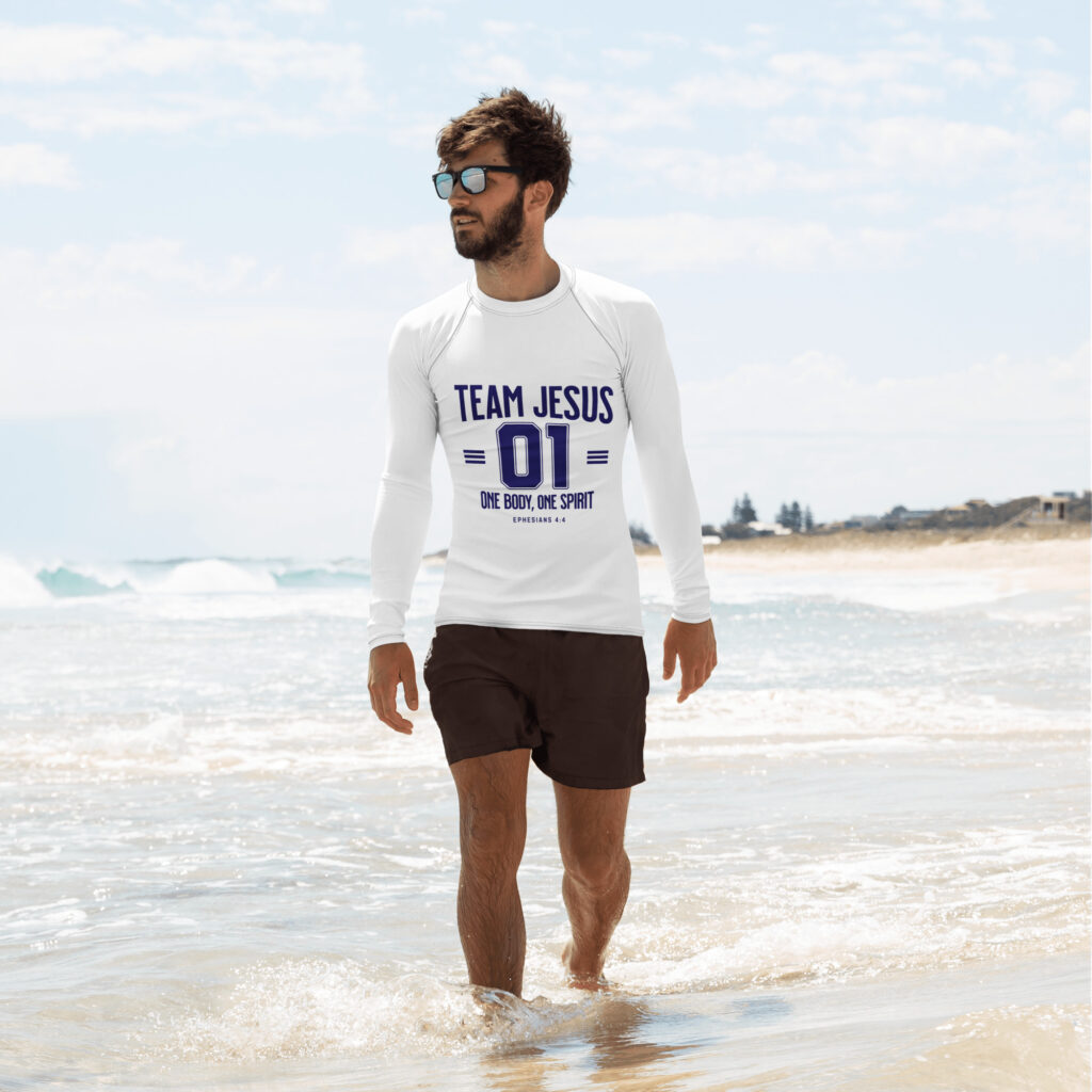 Man walking on the beach wearing a 'Team Jesus' shirt with sunglasses.